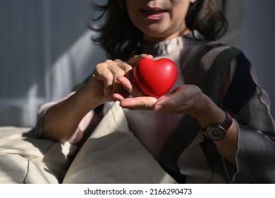 Smiling Middle Aged Woman Holding Heart Shape. Elderly Care, Insurance, Heart Health And Quality Of Life For Elderly Concept