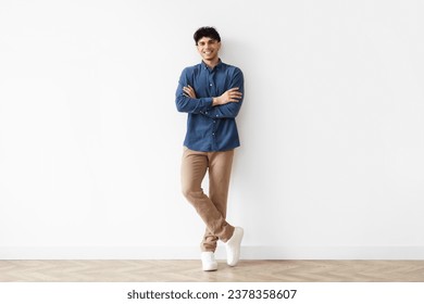 Smiling Middle Eastern Guy Posing With Folded Hands Looking At Camera With Confidence On White Studio Wall Background. Full Length Shot Of Handsome Young Man In Casual - Powered by Shutterstock