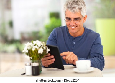 Smiling Middle Ged Man Surfing The Internet Using Tablet Computer At Home