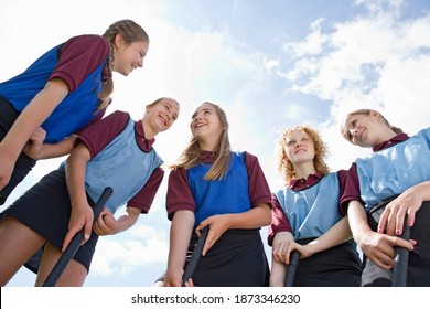 Smiling middle schoolgirls playing field hockey in physical education class - Powered by Shutterstock