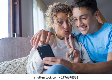 Smiling Middle-aged 40s Mother Rest With Grown-up Son Using Smartphone Together, Happy Young Man Enjoy Family Weekend With Mom Taking A Selfie, Have Fun At Home