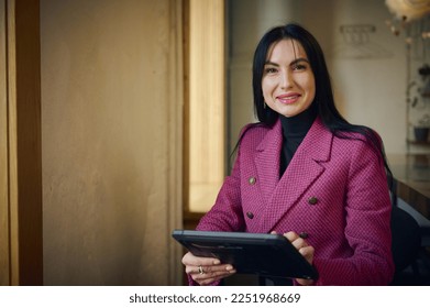 Smiling middle-aged Caucasian business woman, leader entrepreneur, CEO, professional manager holding digital tablet computer, using software applications standing in the interior of modern restaurant - Powered by Shutterstock