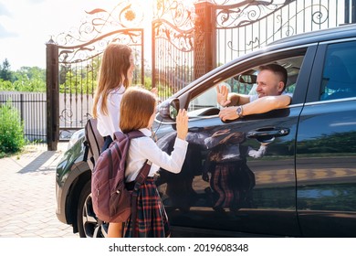 Smiling Middle-aged Father In The Car, Leaving Her Daughters And Sisters In School Uniform At School And Gesturing Goodbye.