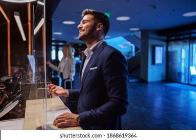 Smiling Middle-aged Man In Formal Wear Standing On The Reception Of A Fancy Hotel And Checking In.