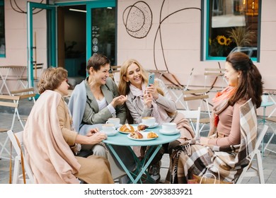 Smiling middle-aged women sitting in a cafe and using a mobile phone - Powered by Shutterstock