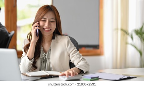 Smiling Millennial Asian Woman Having Phone Conversation, Talking To Business Partners At Workplace