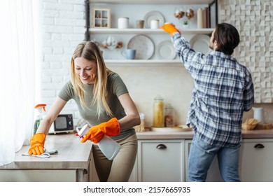 Smiling millennial european woman blonde with rubber gloves and man wipe dust on light kitchen interior, copy space. Hygiene, cleaning at home together and household chores during covid-19 outbreak - Shutterstock ID 2157665935