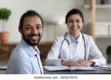 Smiling Millennial Healthy African American Multiracial Patient Satisfied With Visiting Indian Female Doctor, Looking At Camera In Modern Clinic Office Room, Medical Insurance Healthcare Concept.