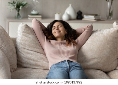 Smiling Millennial Hispanic Woman Lying Relaxing On Couch At Home Sleep Or Take Nap Daydream. Happy Young Latino Female Renter Rest On Sofa In Living Room Breathe Fresh Ventilated Condition Air.