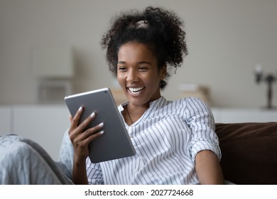 Smiling millennial mixed race female look at pad screen talk speak on video call on gadget. Happy young African American woman use tablet have webcam digital virtual event. Communication concept. - Powered by Shutterstock