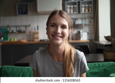 Smiling millennial woman sitting on kitchen sofa talking by videocall dating online looking at camera, video blogger vlogger recording vlog at home, lifestyle vlogging concept, head shot portrait - Powered by Shutterstock