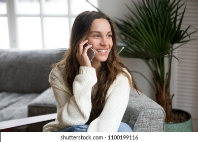 Smiling millennial woman talking on the phone at home, happy young girl holds cellphone making answering call, attractive teenager having pleasant conversation chatting by mobile with friend - Shutterstock ID 1100199116