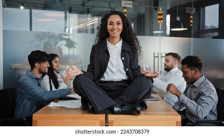 Smiling mindfulness businesswoman happy leader woman sitting at table in lotus position meditating in office meeting relax in meditation background business colleagues discussing project brainstorming - Powered by Shutterstock