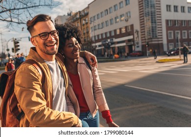 Smiling mix couple enjoying on vacation, young tourist having fun walking and exploring city street during the day. - Powered by Shutterstock