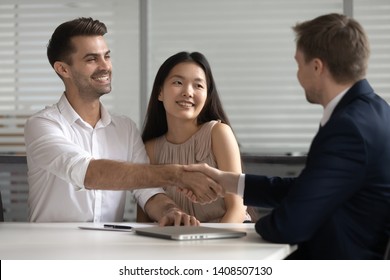 Smiling mixed ethnicity young spouses couple customers handshake bank manager insurer make agreement mortgage loan investment financial deal buy insurance services shake hand of male broker advisor