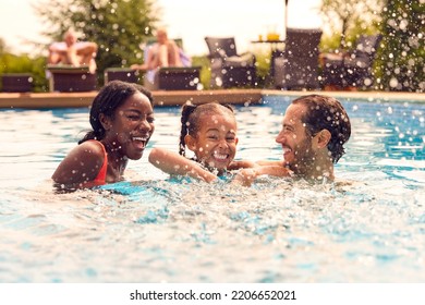 Smiling Mixed Race Family On Summer Holiday Having Fun Splashing In Outdoor Swimming Pool - Powered by Shutterstock