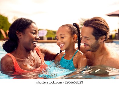 Smiling Mixed Race Family On Summer Holiday Having Fun Splashing In Outdoor Swimming Pool - Powered by Shutterstock