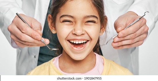 Smiling Mixed Race Girl In A Dental Clinic For Children. Child With A Toothy Smile During Inspection Of Oral Cavity By A Dentist. Close-up