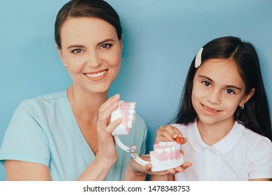 Smiling Mixed Race Girl With Pediatric Dentist Brushing Showing Right Way Brushing Teeth On Blue Background