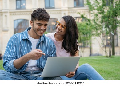 Smiling mixed race students using laptop computer studying, learning language, online education concept. Handsome Indian man and beautiful African American woman working together, selective focus 