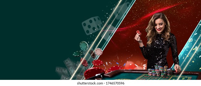 Smiling model in shiny black dress. Showing two red chips, posing at playing table on colorful background with flying money and dices. Poker, casino - Powered by Shutterstock
