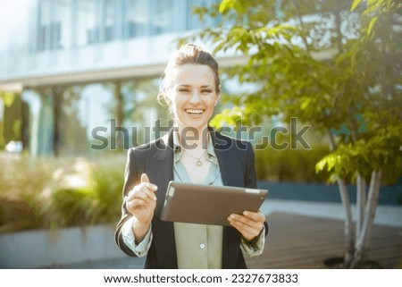 smiling modern 40 years old woman employee near business center in black jacket with tablet PC.