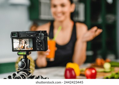 Smiling modern food blogger recording video while drinking fresh organic detox juice in the kitchen. Smoothie for slimming, zero calories drink cocktail full of vitamins - Powered by Shutterstock