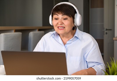 Smiling Modern Old Woman Wear Headset Have Fun While Having Video Call With Children Or On Work Matter