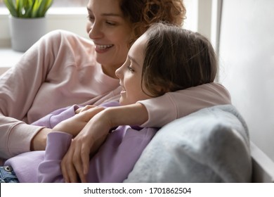 Smiling Mom Embracing Teen Daughter Resting Together At Cozy Home. Happy Family Young Adult Parent Mother And Cute Teenage School Girl Bonding, Talking, Enjoying Sweet Moment Relaxing Lying In Bed.