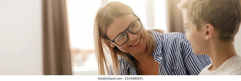 Smiling mom helping her son doing homework studying online using laptop in home - Powered by Shutterstock