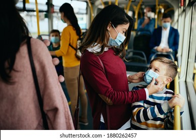 Smiling Mother Ad Her Son Wearing Protective Face Masks In A Public Bus Due To Coronavirus Pandemic.