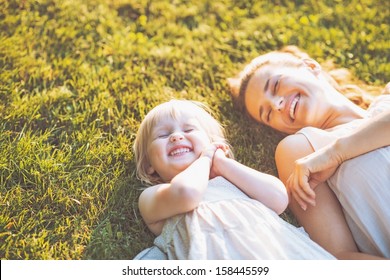Smiling mother and baby laying on meadow - Shutterstock ID 158445599
