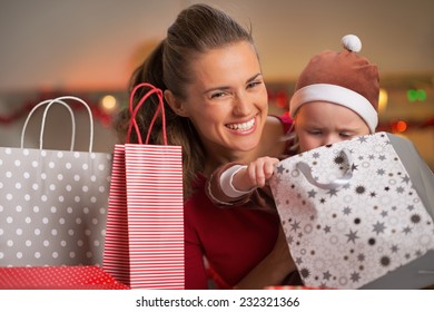 Smiling Mother And Baby Looking In Christmas Shopping Bag