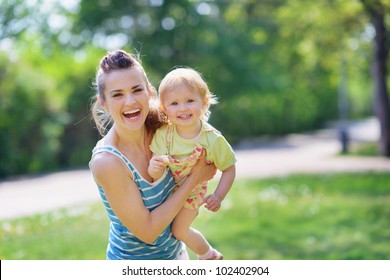 Smiling Mother And Baby Playing In Park