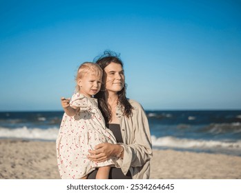 Smiling mother and beautiful daughter having fun on the beach. Portrait of kid embracing her mom during summer. - Powered by Shutterstock