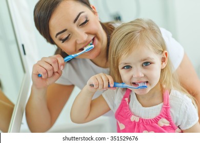 Smiling Mother And The Child To Brush Their Teeth In The Bathroom