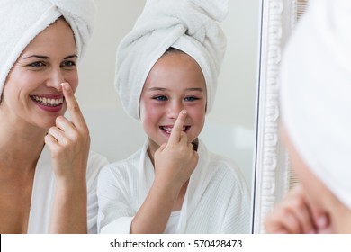 Smiling mother and daughter applying moisturizer on nose in bathroom - Powered by Shutterstock