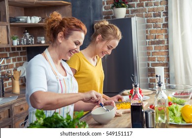 Smiling Mother And Daughter Cooking Together In Kitchen