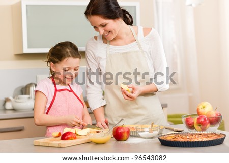 Smiling mother and daughter cutting apples for baking a pie