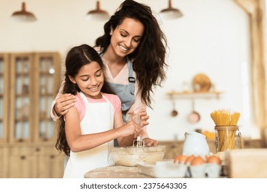 Smiling mother and daughter kneading cookies dough together, engaging in baking session in cozy modern kitchen indoors, embracing joy of pastry preparation and family leisure - Powered by Shutterstock