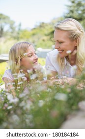 Smiling mother and daughter looking at each other while lying in park - Shutterstock ID 180184184