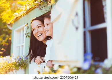 Smiling mother and daughter in playhouse window