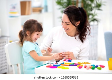 Smiling mother helps a little daughter to sculpt figurines from plasticine. Children's creativity. Happy family - Shutterstock ID 1360389563