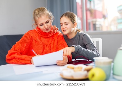 Smiling Mother And Her Happy Teenage Daughter Read Letter From School With Test Results, Sitting Indoor