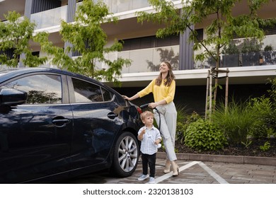 Smiling mother and her little son charging their electric car on the street. - Powered by Shutterstock