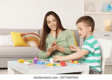 Smiling mother and her son sculpting with play dough at table indoors - Powered by Shutterstock