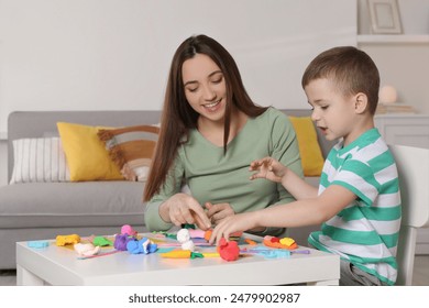 Smiling mother and her son sculpting with play dough at table indoors - Powered by Shutterstock