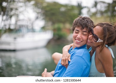 Smiling Mother Hugging Her Teenage Son From Behind.