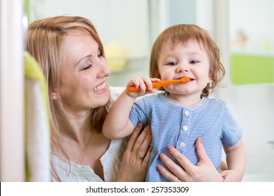 Smiling Mother And Kid Son Brushing Teeth In Bathroom