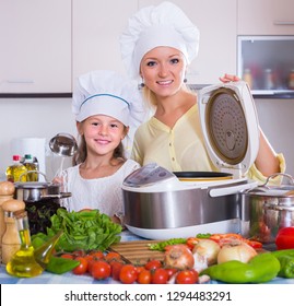 Smiling Mother And Little Daughter With Crockpot In Home Kitchen
